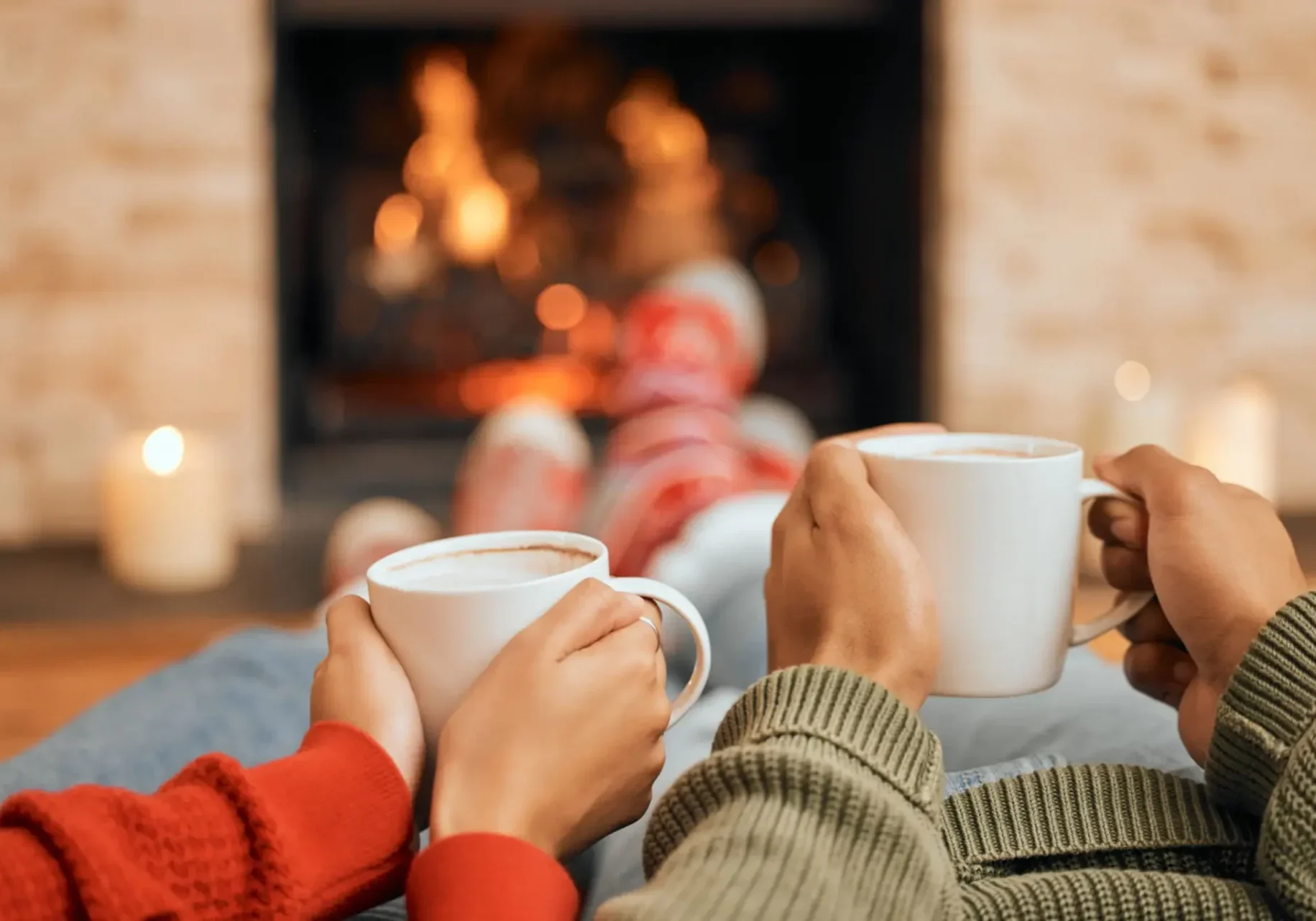 Cozy fireplace scene with mugs and socks.
